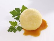 Potato dumpling with gravy and parsley  on white surface — Stock Photo