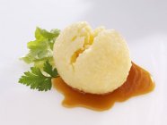 Potato dumpling with gravy and parsley over white surface — Stock Photo