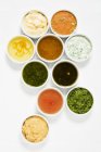 Top view of assorted salad dressings in white dishes on white surface — Stock Photo