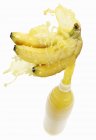 Sumo de banana salpicando para fora da garrafa — Fotografia de Stock