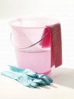 Secchio per la pulizia rosa con acqua e guanti di gomma — Foto stock