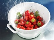 Washing strawberries in colander — Stock Photo
