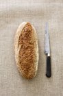 Bread and knife on textile — Stock Photo