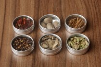 Assorted spices in small tins on wooden surface — Stock Photo