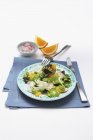 Весенний салат на голубой тарелке над полотенцем с ножом и вилкой — стоковое фото