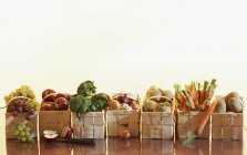 Фрукты и овощи в корзинах на деревянной поверхности на белом фоне — стоковое фото