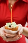 Donna che tiene cupcake con candela — Foto stock