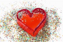 Closeup view of jelly heart and sprinkles on white surface — Stock Photo