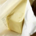 Vista de cerca de la barra de mantequilla en papel envoltura - foto de stock