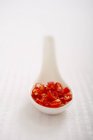 Rote Chilischoten auf weißem Löffel über weißer Oberfläche geschnitten — Stockfoto