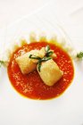 Closeup view of buns tied with herb on red sauce and white dish — Stock Photo