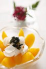 Nahaufnahme von geschnittenem Pfirsich mit Blütenblättern und Kräutern in Glasschale — Stockfoto