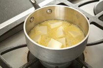 Vue surélevée de la fonte du beurre dans une casserole sur la cuisinière à gaz — Photo de stock