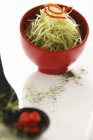 Salade de pousses de bambou dans un bol rouge sur une surface blanche — Photo de stock