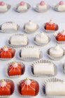 Red and white petit fours in paper cases — Stock Photo