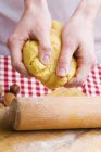 Vue rapprochée des mains pétrissant la pâte à biscuits — Photo de stock
