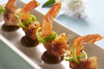 Closeup view of fried prawn kebabs with limes and a tamarind sauce — Stock Photo