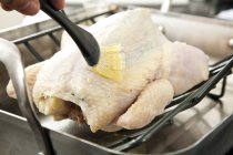Mano humana cepillando pollo con mantequilla - foto de stock