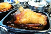 Close up of  Brushing stuffed roast goose with roasting juices — Stock Photo