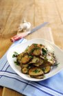 Fried Jerusalem artichoke slices with garlic and parsley on white plate  over towel — Stock Photo