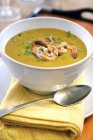 Pumpkin soup with garlic prawns in white bowl over towel with spoon — Stock Photo