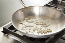 Sauteing рубаного часнику в сковороду з оливковою олією — стокове фото
