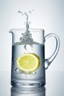 Lemon falling into jug of water — Stock Photo