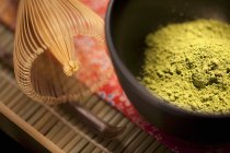 Vista ravvicinata del tè verde giapponese Matcha in polvere in una ciotola cerimoniale nera Matcha con frusta — Foto stock