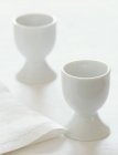Closeup view of two white egg cups with a napkin — Stock Photo