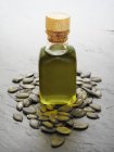 Closeup view of pumpkin seed oil and pumpkin seeds on grey surface — Stock Photo