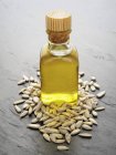 Vista de primer plano del aceite de girasol y las semillas en la superficie gris - foto de stock