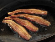 Listras de bacon Fritando em Skillet — Fotografia de Stock