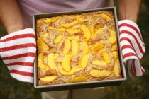 Closeup cropped view of person holding fresh peach cobbler — Stock Photo