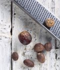 Целые мускатные орехи с теркой — стоковое фото