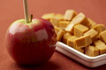 Closeup view of apple on stick and caramel candies — Stock Photo