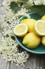 Limões em prato e flores mais velhas — Fotografia de Stock
