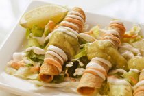 Closeup view of fried Taquitos on lettuce leaves — Stock Photo
