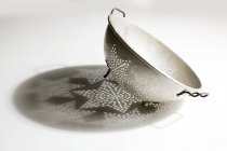 Nahaufnahme von antiken Metallsieb mit Schatten auf weißer Oberfläche — Stockfoto