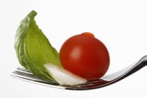 Tomato with mozzarella and basil on fork — Stock Photo