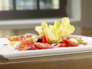 Une salade de tomates avec trois différents types de tomates sur assiette blanche — Photo de stock