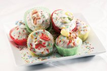 Muffins con glaseado y espolvoreos de colores - foto de stock