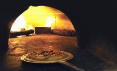 Pizza in wood-fired oven — Stock Photo