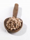 A pile of chickpeas on a wooden spoon on white background — Stock Photo