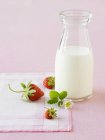 Vista close-up de garrafa de leite e morangos — Fotografia de Stock