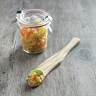 Closeup view of homemade mango salsa on wooden spoon and in glass jar — Stock Photo
