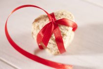 Heart-shaped biscuit tied with red ribbon — Stock Photo