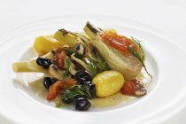 Fenchel in Folie gewickelt, gekocht mit Oliven, Tomaten und Kartoffeln auf weißem Teller — Stockfoto