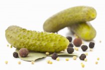 Cornichons with spices  on white surface — Stock Photo