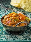 Vegetable curry in metal pan over green tablecloth — Stock Photo