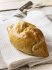 Closeup view of Cornish pasty on folded white towel with knife and fork — Stock Photo